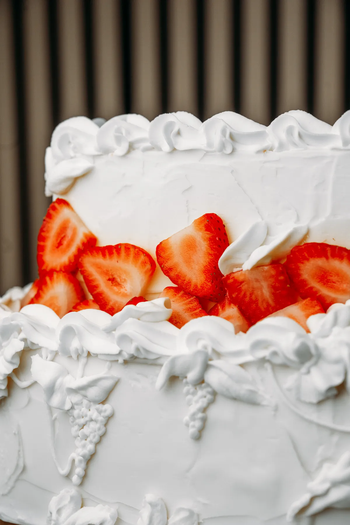 Primer plano de un borde de crema de mantequilla hecho a manga con fresas partidas por la mitad debajo.