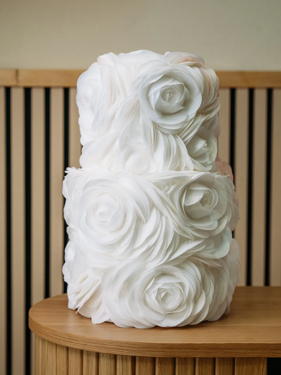 Tarta de dos pisos cubierta por completo de grandes rosas blancas de crema de mantequilla con volantes.